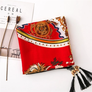 Detail of red floral cotton scarf with black tassels and decorative wooden beads