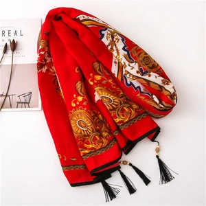 Close-up of red cotton linen scarf featuring floral motifs and handmade wooden bead tassels