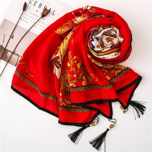 Detail of red floral scarf featuring black hem, tassels, and natural wooden bead accents