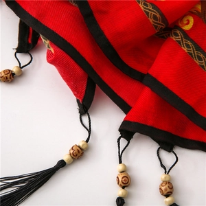 Detail of red cotton linen shawl featuring black fringe tassels and ethnic wooden beads