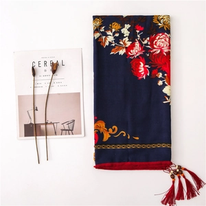 Close-up of linen scarf showing red floral print, wooden beads, and long tassel details