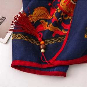 Detail of navy cotton linen scarf with red fringe, wooden beads, and floral pattern