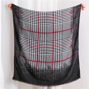 Close-up of lightweight black and white plaid scarf with bold red stripes and fringe trim