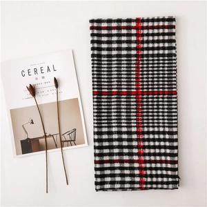 Classic black and white plaid scarf with red stripes on a minimalist white backdrop