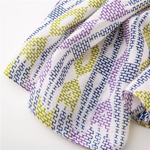Detailed view of white cotton-linen scarf with purple and green geometric embroidery