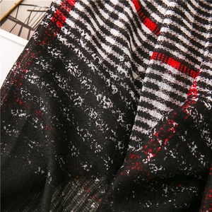 Close-up of the delicate texture and red black plaid pattern on a lightweight scarf