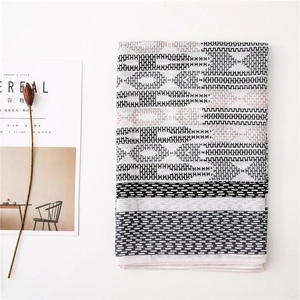 Detailed flat lay of geometric pattern cotton scarf with tassels and minimalist decor