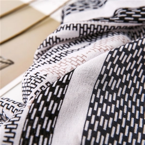 Detail shot of lightweight scarf featuring elegant geometric H patterns and soft fringe