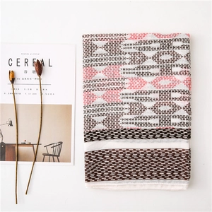 Close-up of geometric H-pattern linen shawl with fringe and lifestyle magazine background