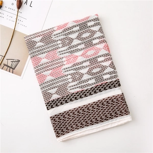 Flat lay of a cotton-linen scarf featuring pink and black geometric diamond patterns