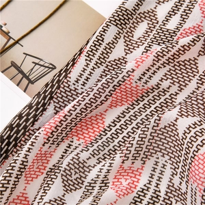 Detail of soft scarf fabric with geometric H-pattern and red accents on magazine