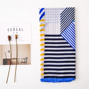 Detail of blue and yellow geometric pattern scarf with refined edge stitching and soft texture