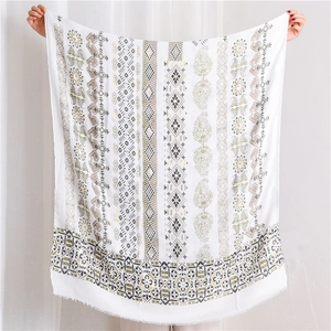 Detail of bohemian cotton linen scarf with golden patterns and raw fringe edges