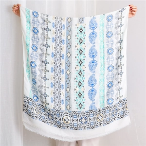Detailed view of bohemian floral cotton linen shawl with intricate fringe edge in white