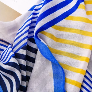 Detail of soft fabric scarf showing geometric patterns and delicate rolled edges