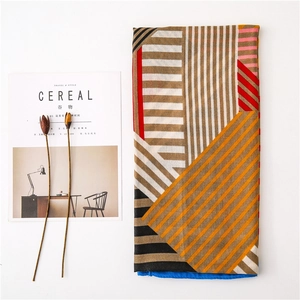 Detailed flat lay of long scarf with red blue geometric patterns and artistic stripes