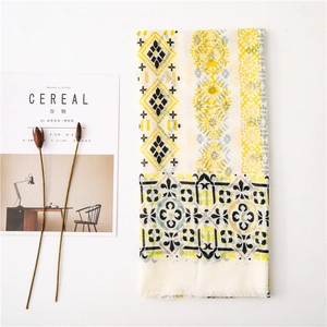 Detailed close-up of ivory cotton scarf with yellow vine prints and white fringes