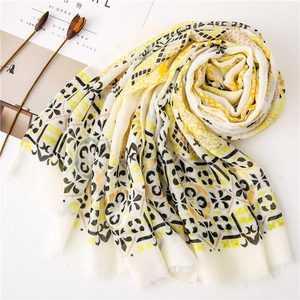 Close-up of cotton linen scarf with golden floral patterns and soft tassel edges