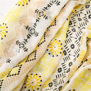 Detail shot of cotton linen scarf with golden floral patterns and soft fabric texture