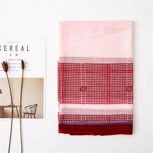 Detailed close-up of pink houndstooth scarf with lightweight fabric and tassels