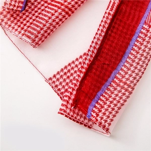 Close-up of red and white houndstooth scarf with purple border and stitched hem detail