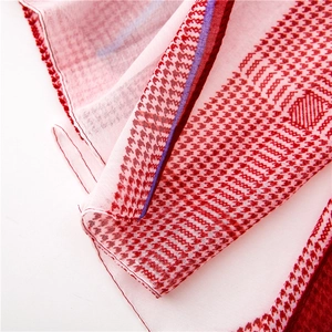 Detail of red and white houndstooth scarf showing lightweight fabric texture and purple accent