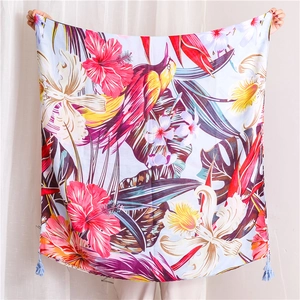 Détail du foulard imprimé fleurs et oiseaux tropicaux avec pompons bleus sur tissu léger