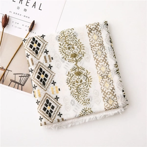Detailed close-up of bohemian linen scarf with paisley patterns and soft white tassels