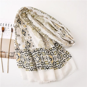 Close-up of cotton linen shawl with gold foil paisley patterns and fringe edges
