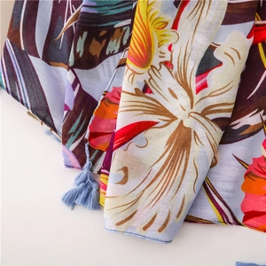 Détail de l'imprimé floral et oiseaux sur écharpe en lin avec pompons bleus