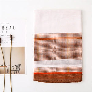Detail of folded houndstooth scarf with orange and brown blocks on a white background