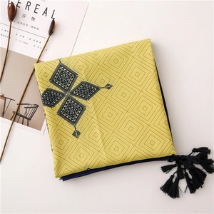 Detail of yellow geometric scarf featuring ethnic blue patterns and fringe tassels