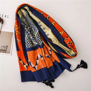 Close-up of geometric pattern scarf with navy and orange prints and black tassels