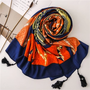 Detail of bohemian scarf with geometric diamond patterns and navy blue tassel accents