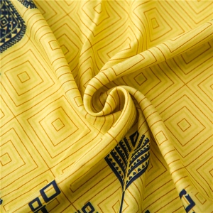 Close-up of yellow silk scarf fabric with navy blue geometric and ethnic patterns