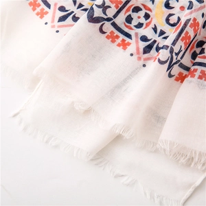 Detail of white cotton linen shawl featuring ethnic geometric prints and frayed edges