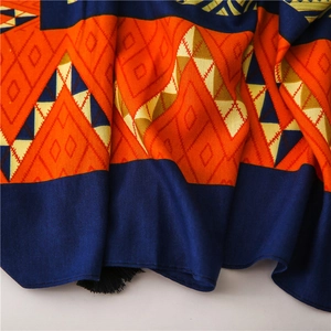 Close-up of geometric pattern scarf with colorful triangles and black fringe trim