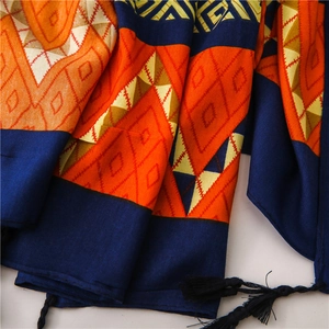 Detail of geometric scarf with orange diamond patterns and long black tassels