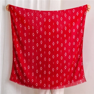 Detail of red geometric diamond pattern scarf with soft frayed edges being held open