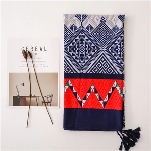 Detail of bohemian geometric print scarf with red zigzag patterns and fringe tassels