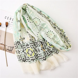 Detailed macro view of ivory linen shawl featuring green leaf prints and short fringe edges
