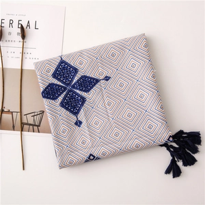 Detailed embroidery and dark blue tassel on a geometric pattern linen square scarf