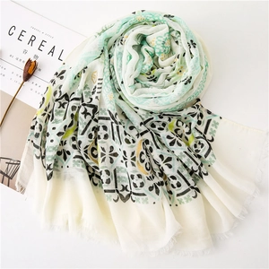 Close-up of cotton linen scarf with bohemian paisley pattern and fringed edges on white surface