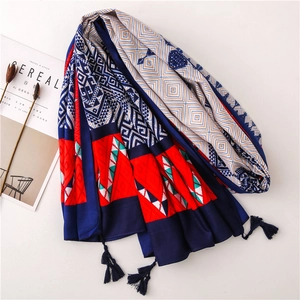 Detail of bohemian geometric print scarf with dark blue tassels on white background