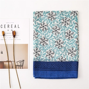 Dettaglio flat lay di scialle in cotone a fiori con bordo blu e rivista Cereal