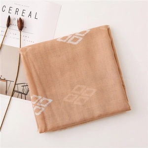 Detail view of apricot geometric diamond pattern scarf with decorative dried flowers