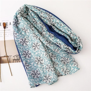 Dettaglio di sciarpa floreale in cotone lino con bordi arrotolati blu e design leggero