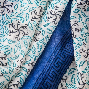 Dettaglio di sciarpa in cotone e lino con motivi floreali blu e bordi geometrici