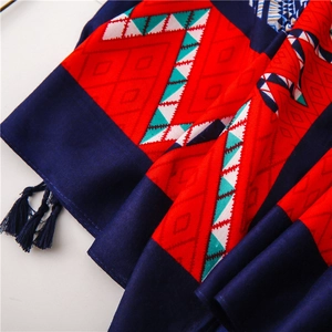 Detail of ethnic geometric diamond pattern scarf with navy blue decorative tassels