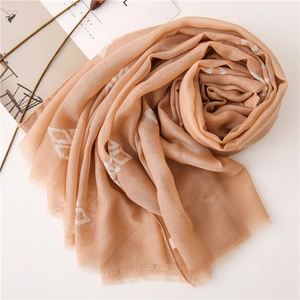 Minimalist beige fringed scarf with white geometric squares in a soft spiral layout